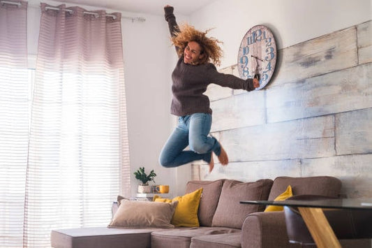 Woman joyfully jumping in a bright living room, showcasing a happy and active lifestyle.
