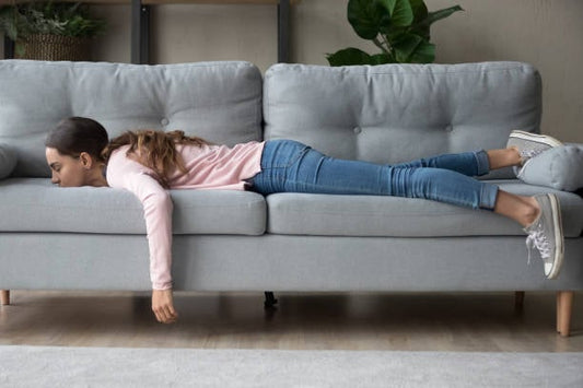 Girl lying exhausted on a couch, illustrating fatigue and low energy levels.