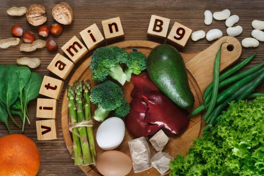 Fresh foods rich in Vitamin B9, including vegetables, eggs, and nuts on a wooden cutting board.