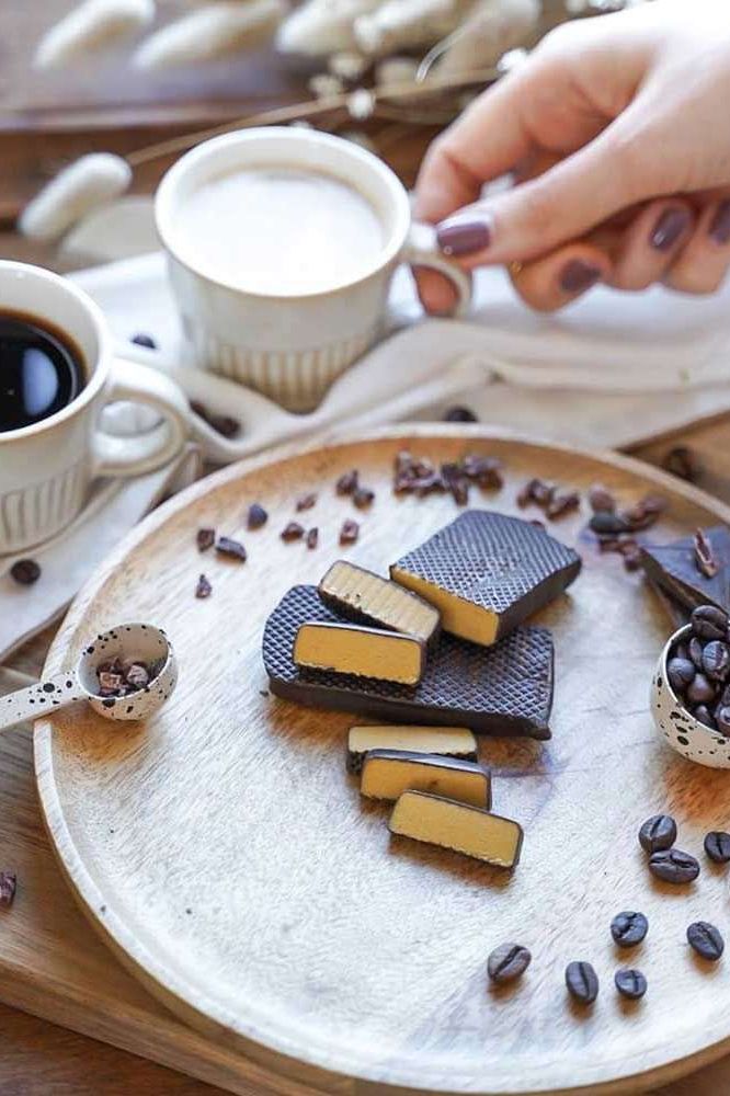 Delicious vegan AbsoRICE Move Bars on a wooden plate, surrounded by coffee cups and coffee beans.