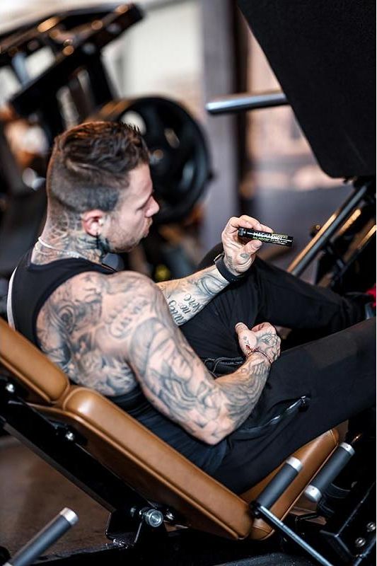 Man with tattoos holding BioTechUSA Magna Shot in the gym, focusing on fitness and wellness.