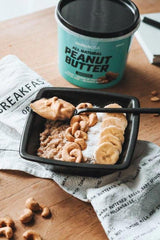 Delicious bowl of oatmeal topped with BioTechUSA peanut butter, banana slices, and cashews.