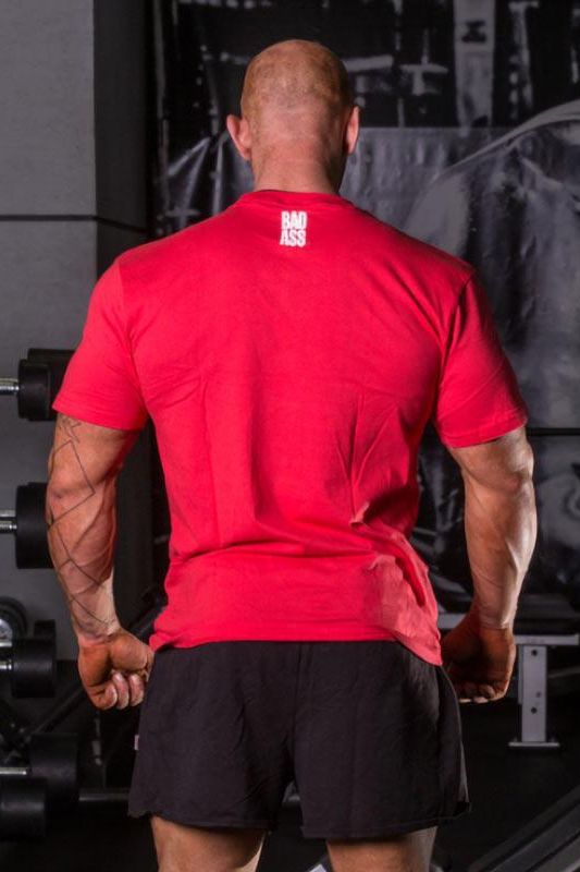Back view of a muscular man wearing a red FA Fitness Authority T-shirt with 'BAD ASS' print, showcasing athletic appeal.