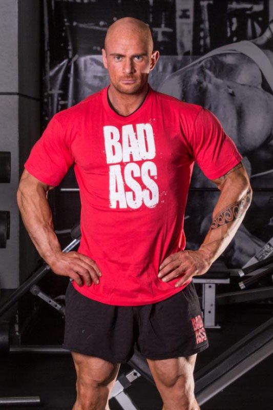 Model wearing FA Fitness Authority T-Shirt Double Neck Bad Ass in gym, showcasing athletic fit and comfort.