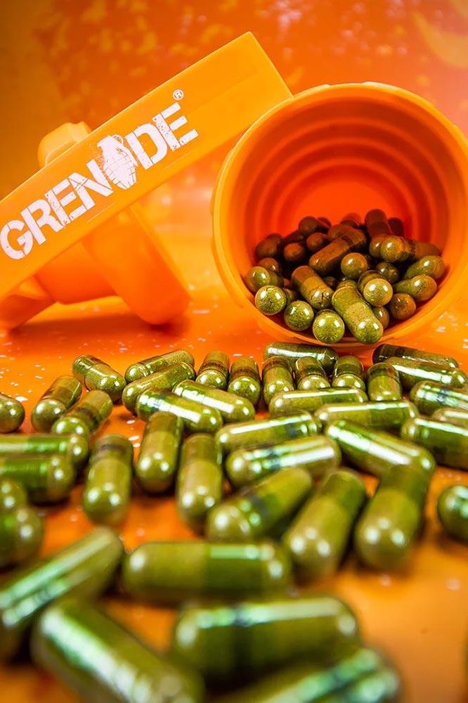 Grenade Thermo Detonator capsules spilled from an orange bottle with vibrant background, ideal pre-workout stimulant.