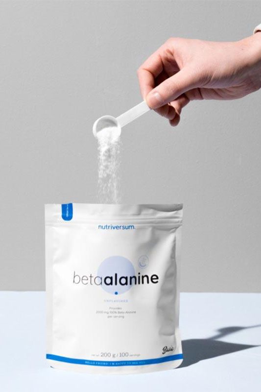 Person scooping Nutriversum Beta Alanine powder from a 200g pouch.