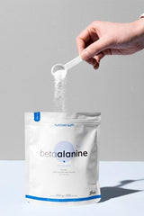 Person scooping Nutriversum Beta Alanine powder from a 200g pouch.