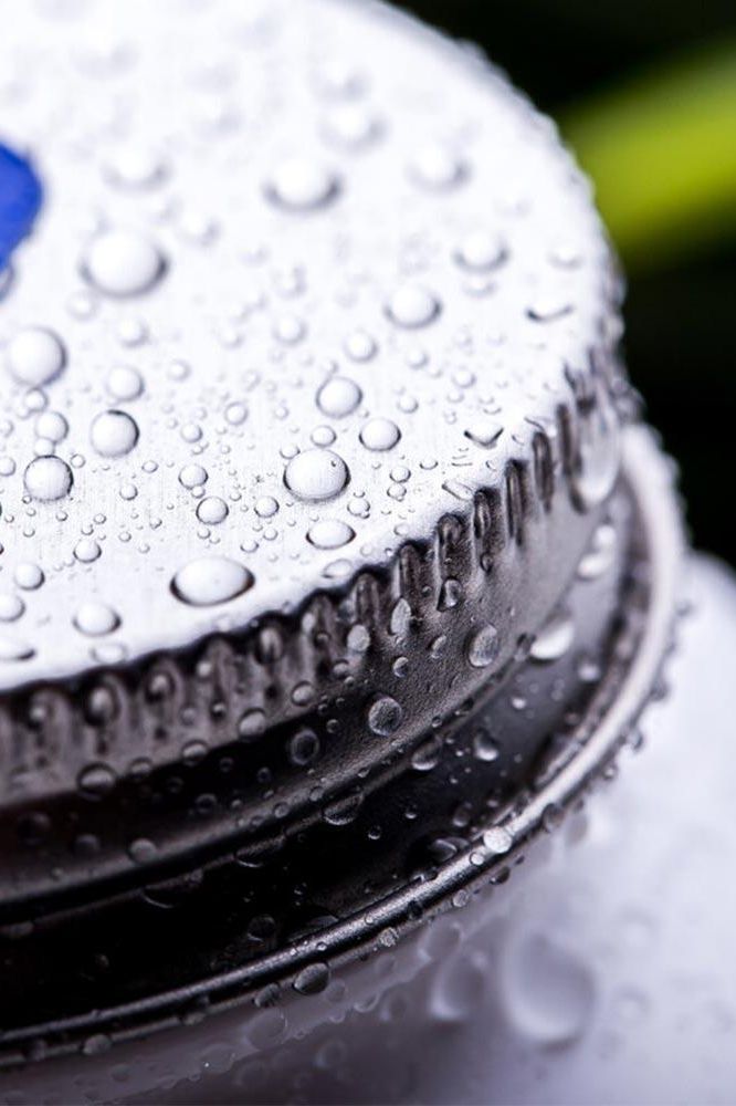 Close-up of a silver bottle cap covered in water droplets, highlighting its sleek design.