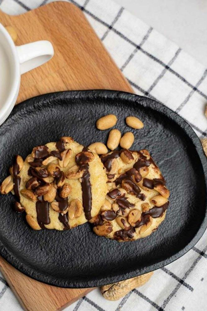 Nutriversum cookies with chocolate drizzle and nuts on a black plate, perfect healthy snack option.