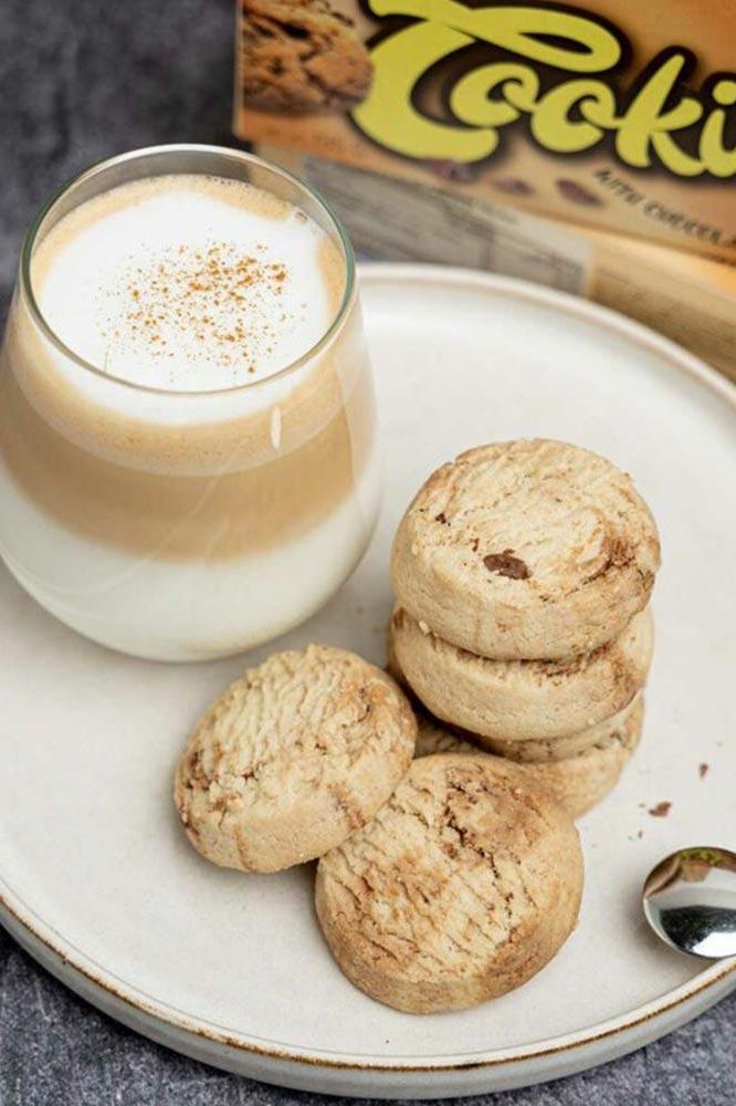 Delicious Nutriversum cookies on a plate with a glass of latte, a healthy snack option.