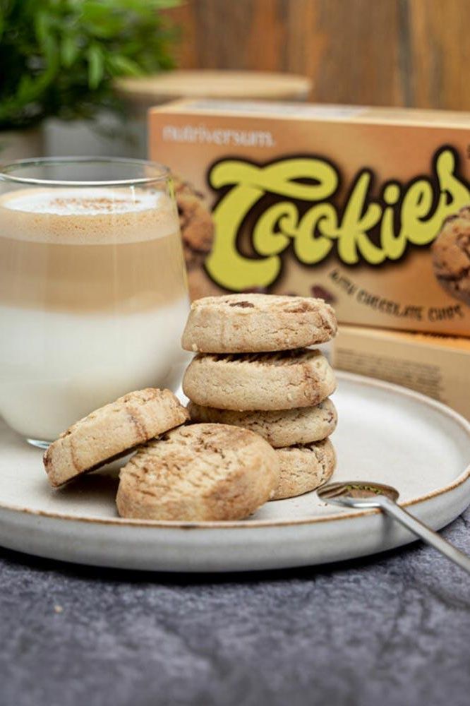Healthy Nutriversum cookies on a plate with a glass of coffee, showcasing peanut and chocolate chip flavors.