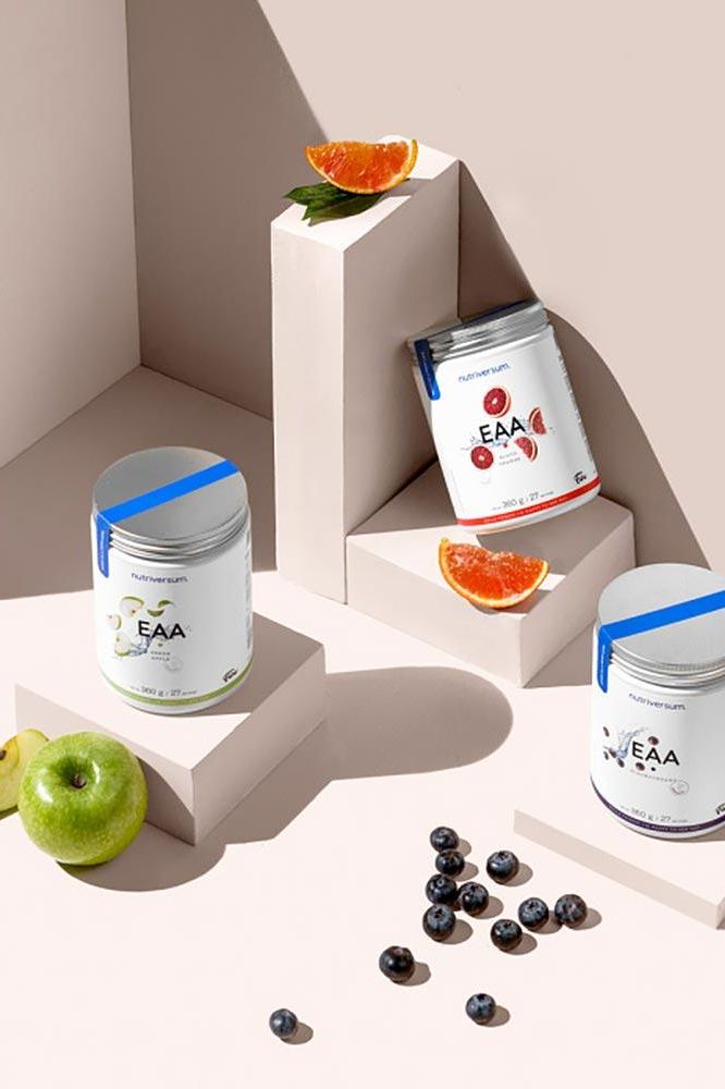 Nutriversum EAA supplements displayed with fruits in a minimalist setting, highlighting vibrant flavors and packaging.