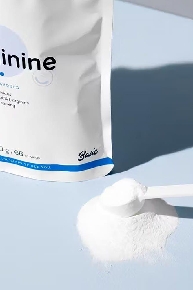 Nutriversum L-Arginine unflavored powder in a scoop on a blue background.