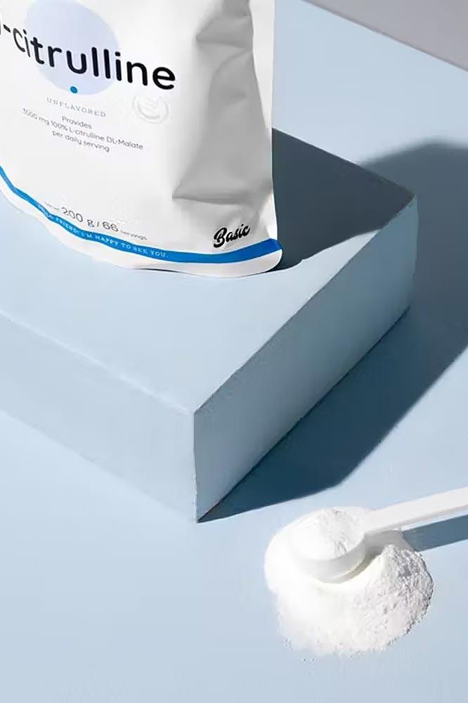 Nutriversum L-Citrulline unflavored powder on a blue surface with a scoop.