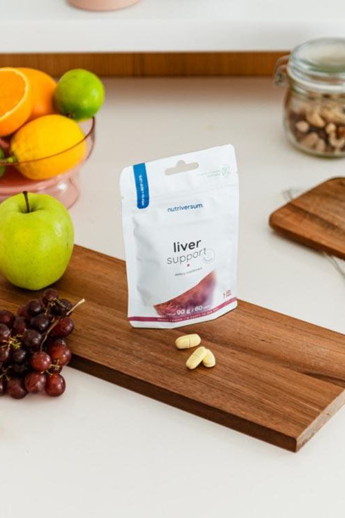 Nutriversum Liver Support supplement on a wooden surface with fresh fruits.