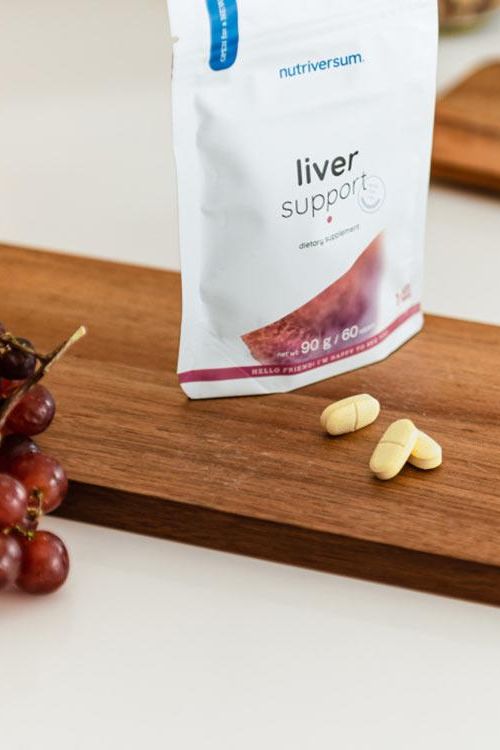 Nutriversum Liver Support dietary supplement tablets with packaging on wooden surface.