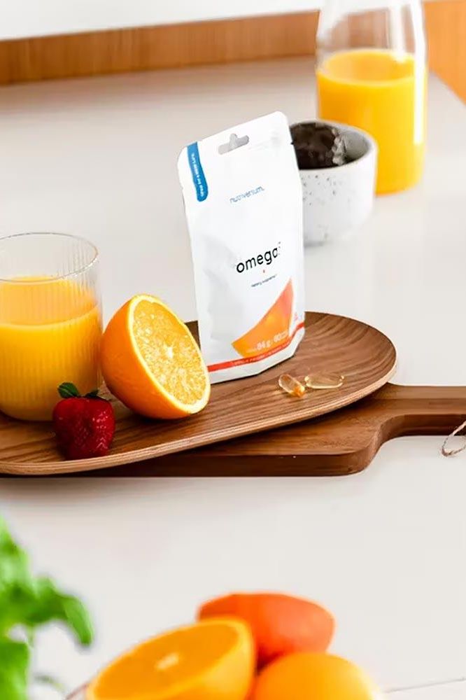 Nutriversum Omega 3 softgels with orange slices and juice on a wooden board.