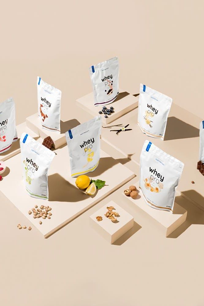 Nutriversum Whey PRO - PURE protein powder packages in various flavors, displayed on a minimalistic design, showcasing premium quality.
