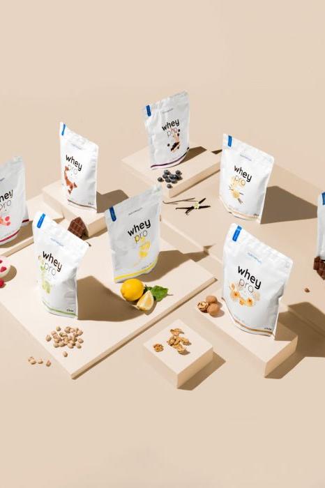 Various flavors of Nutriversum Whey PRO - PURE protein powder displayed on platforms.