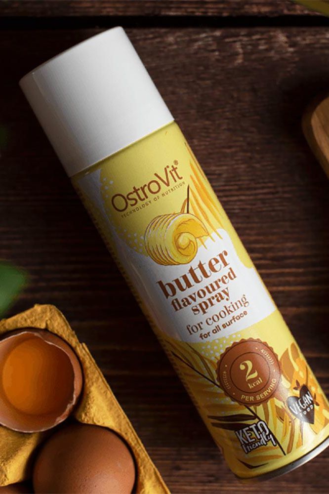 OstroVit butter flavoured cooking spray bottle on a wooden surface, ideal for healthy cooking and easy portion control.