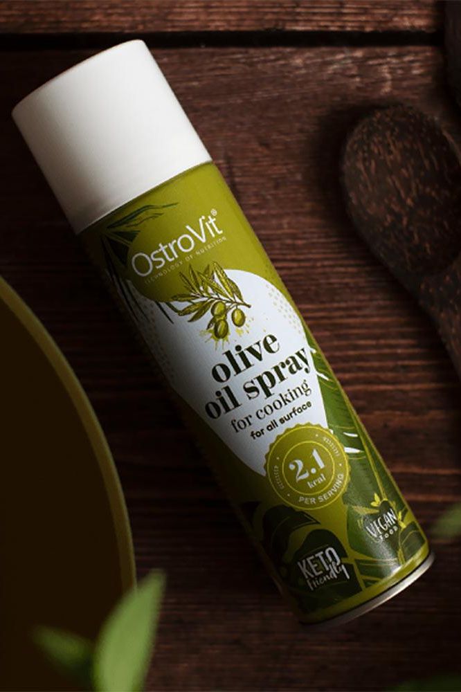 OstroVit olive oil cooking spray bottle on wooden surface, promoting healthy cooking and oil options.