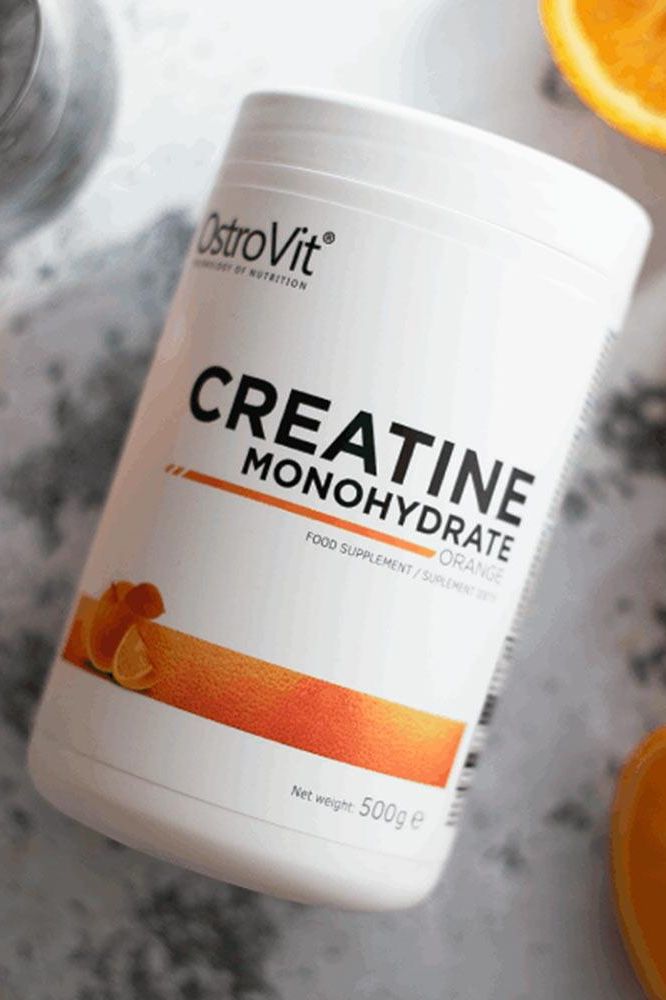OstroVit Creatine Monohydrate 500g product container with orange flavor, food supplement for strength and endurance.