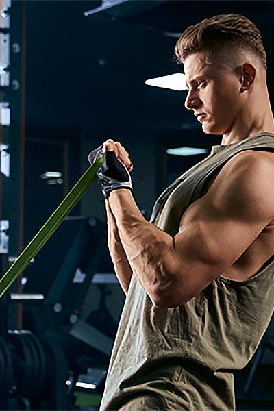 Man exercising with a resistance training band in a gym, focusing on strength building and fitness.