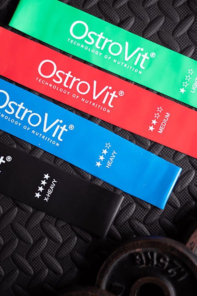 OstroVit training bands in green, red, blue, and black colors on a textured background, ideal for effective workouts.