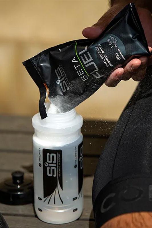 Pouring Science in Sport Beta Fuel Powder into a sports water bottle for optimal hydration.