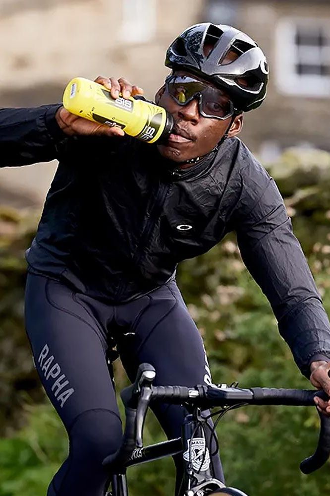 Cyclist drinking from a Science in Sport bottle while riding a bike outdoors.