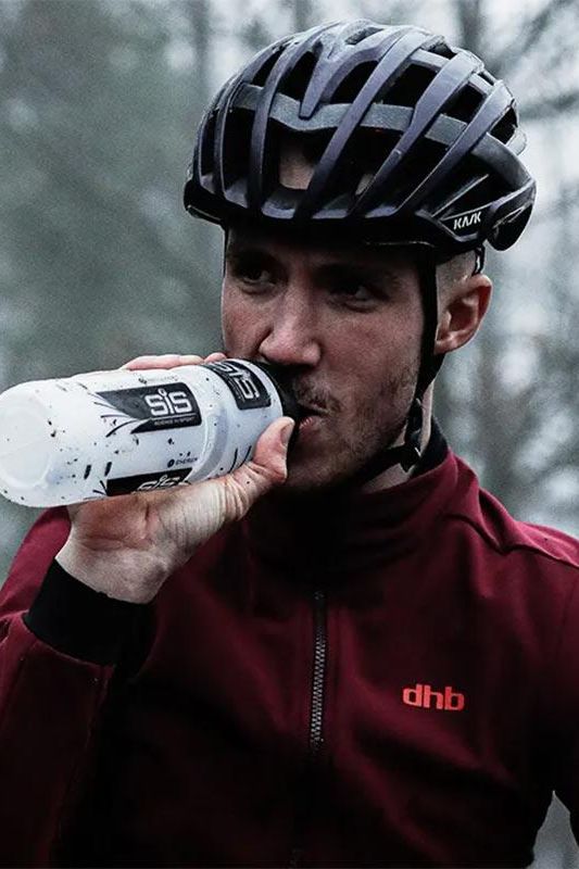 Athlete in a cycling helmet drinking Science in Sport GO Electrolyte Powder for hydration during training.