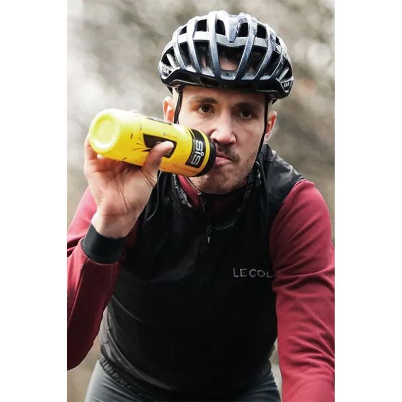Cyclist wearing a helmet and riding gear, sipping Science in Sport GO Energy Powder for hydration during training.