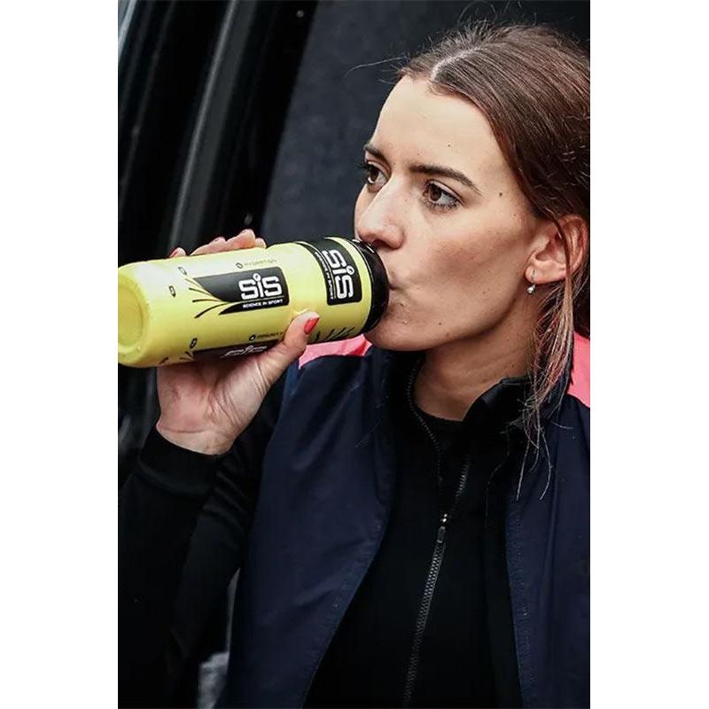 Woman drinking Science in Sport GO Energy Powder from a bottle during outdoor training.