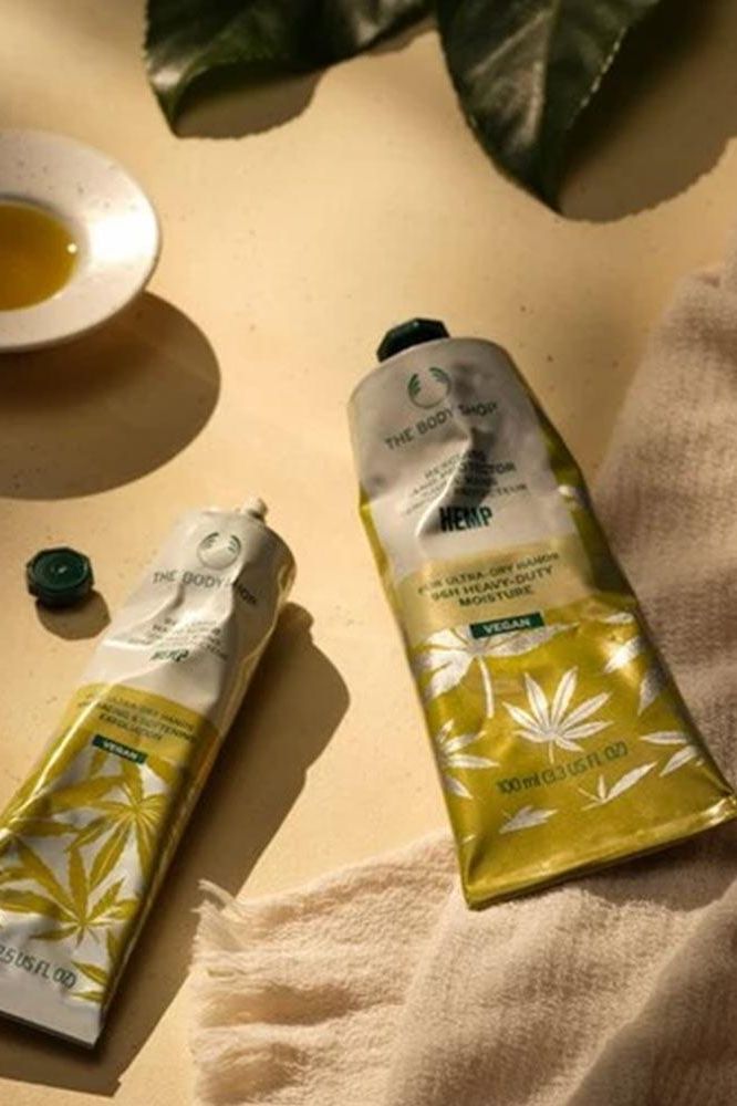 The Body Shop Hemp Vegan Rescuing Hand Cream tubes on a textured surface with leaves.