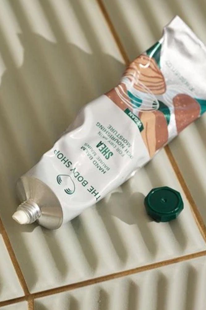 The Body Shop Shea Hand Balm tube on tiled surface, showcasing its rich vegan formula for dry skin.