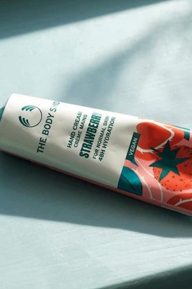 The Body Shop Strawberry Vegan Hand Cream tube on a light surface, 30 ml for 48 hours hydration.