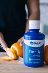 Trace Minerals Liquid Fiber 14g bottle on a kitchen counter with sliced oranges, promoting healthy digestion.