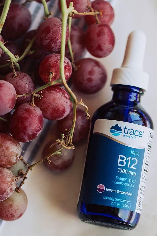 Trace Minerals Liquid Ionic B12 1000 mcg bottle next to fresh grapes, dietary supplement for energy and cardiovascular health.