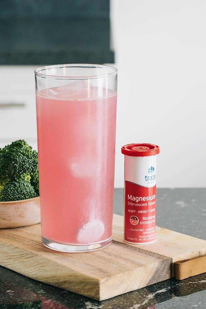 Trace Minerals Magnesium Effervescent Tablets with a pink drink and broccoli on a wooden board, showcasing health benefits.