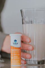 Trace Minerals Magnesium Effervescent Tablets next to a glass of orange drink, promoting energy and heart health.