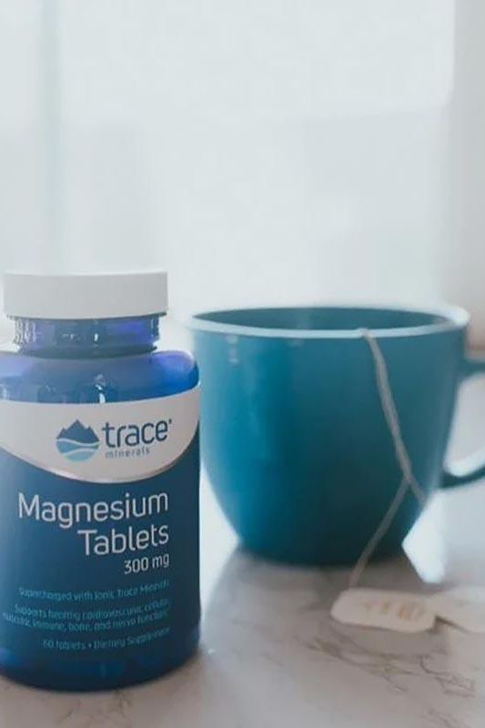 Trace Minerals Magnesium Tablets 300 mg bottle beside a blue cup, promoting healthy magnesium levels.