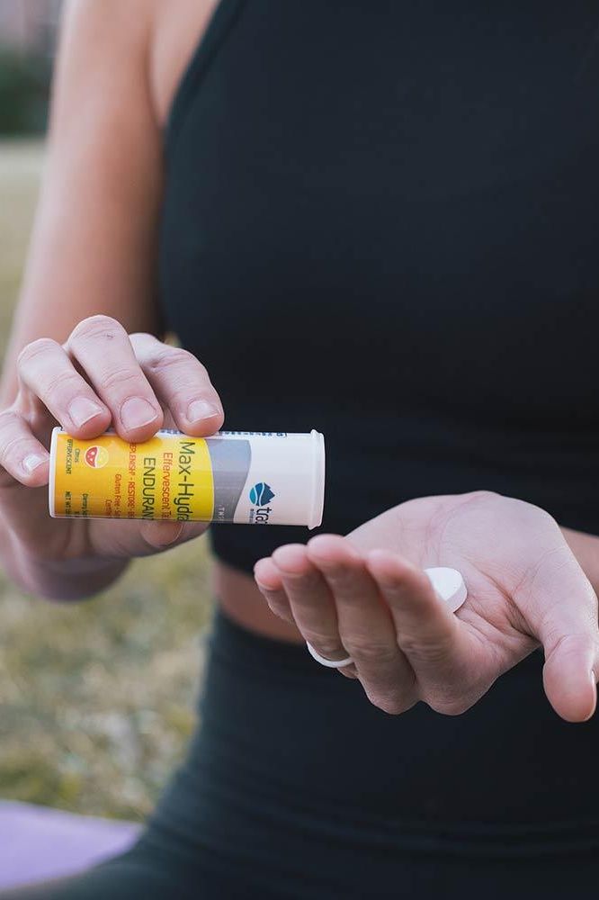 Person holding Trace Minerals Max-Hydrate Effervescent Tablets for hydration and muscle support.