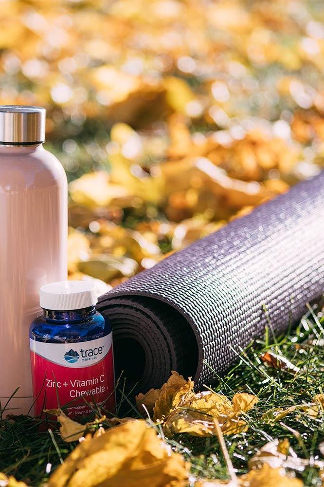 Trace Minerals Zinc + Vitamin C chewable bottle on a yoga mat among autumn leaves for immune support.