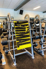 Universal Nutrition Animal Gym Towel hanging on a weight rack in a gym, featuring a bold yellow design.
