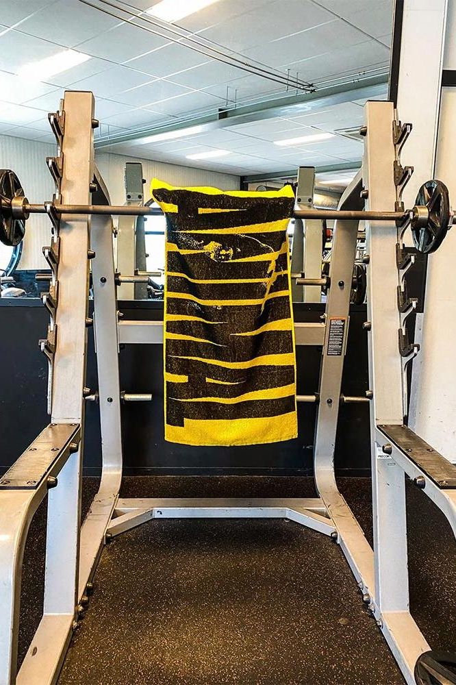 Universal Nutrition Animal Gym Towel hanging on a squat rack in a gym, featuring striking epic design and vibrant colors.