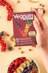 Vegnum Energy-D supplement box held above a bowl of fruits, promoting energy and immune support, 30 capsules.