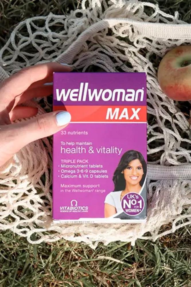 Wellwoman Max capsules packaging held in hand on natural background, promoting health and vitality for women.