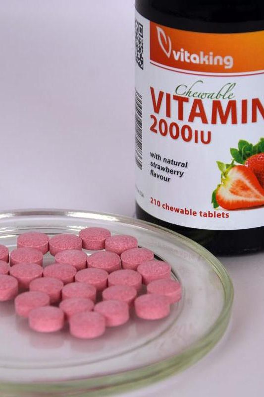 Vitaking Vitamin D3 2000 IU chewable tablets in strawberry flavor on a plate next to the bottle.